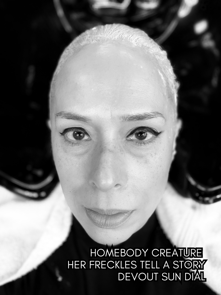 Black-and-white close-up selfie of Baroque Medusa during hair processing, paired with a haiku about freckles, identity, and inward devotion.