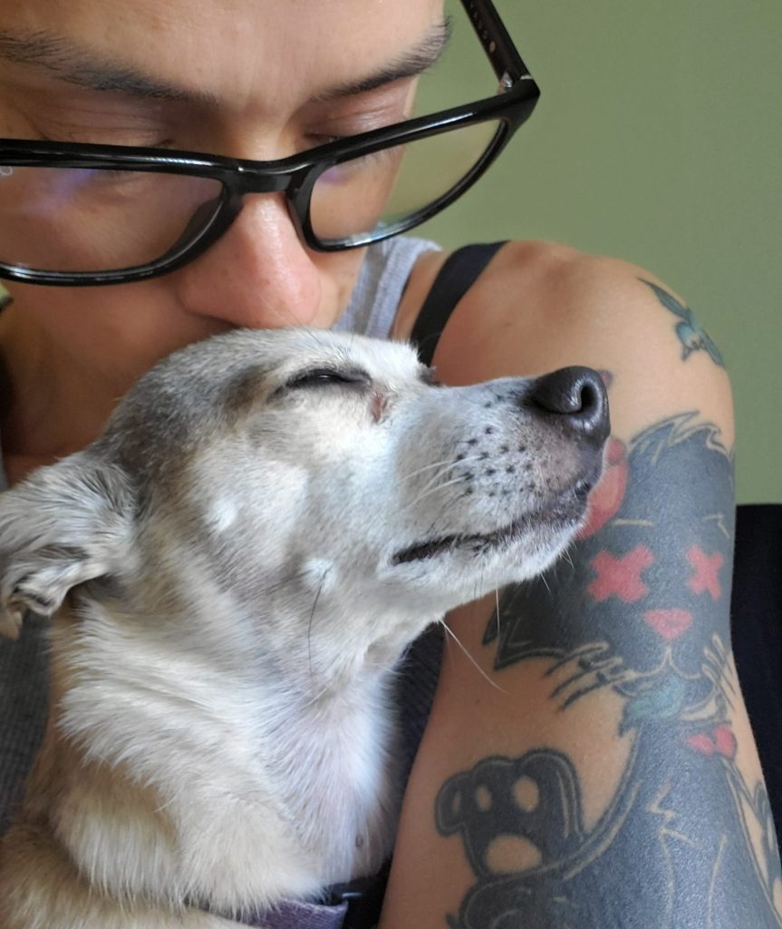 Close-up portrait of Baroque Medusa kissing Fenway on the forehead while holding her gently in an intimate moment of love and comfort.