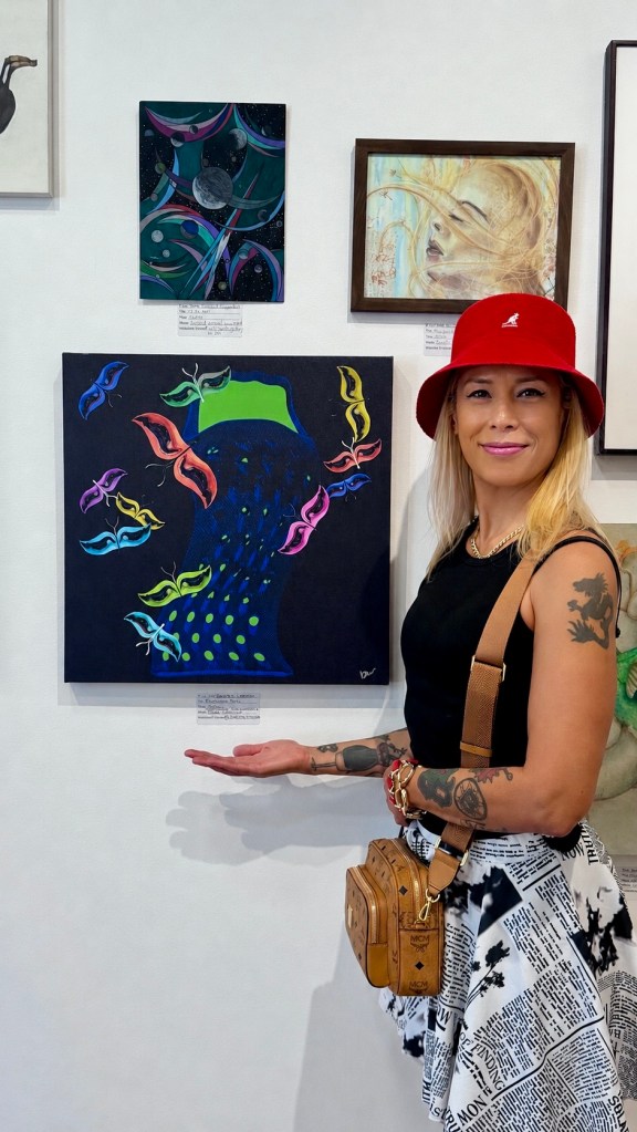 Baroque Medusa posing beside her abstract artwork Frenzied Pull during the Free 4 All 2026 exhibition at the Claremont Lewis Museum of Art.